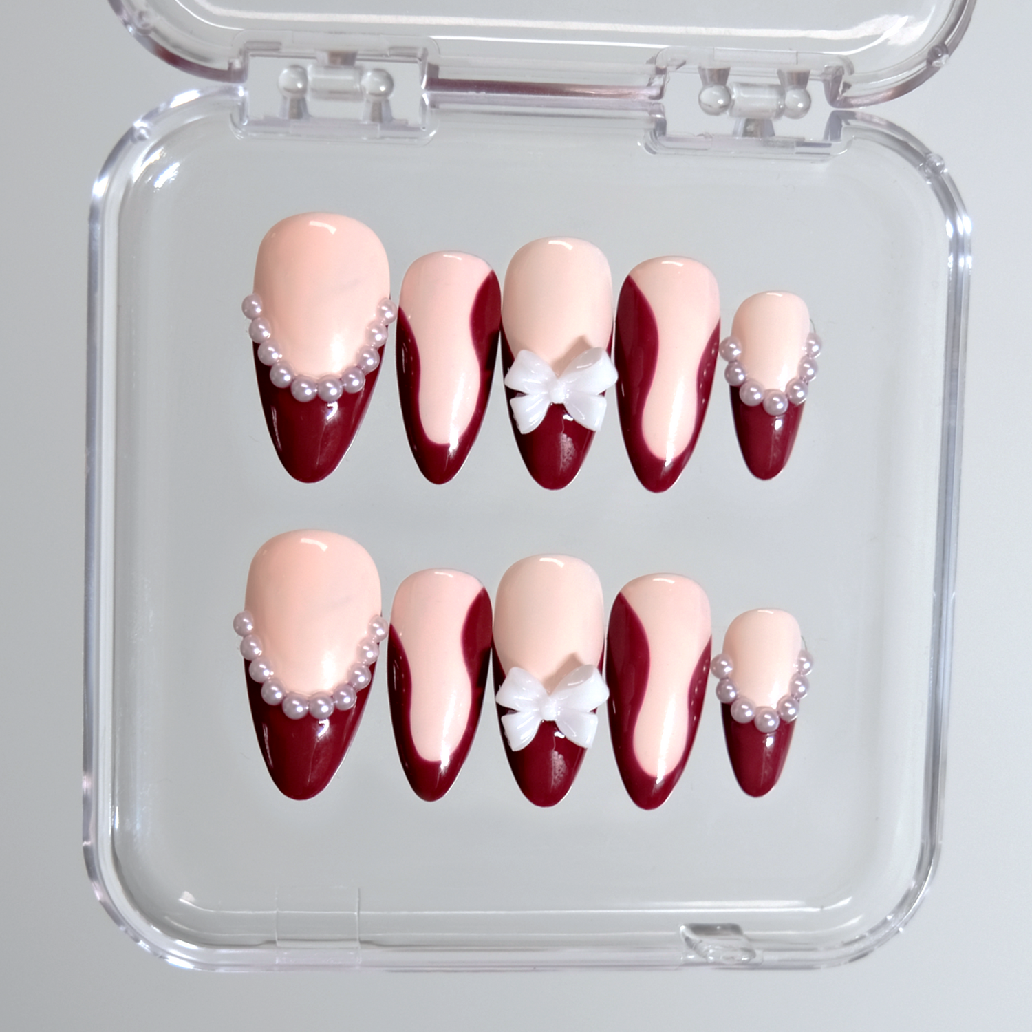 Almond gel nails in dark red with pearl details and white bows